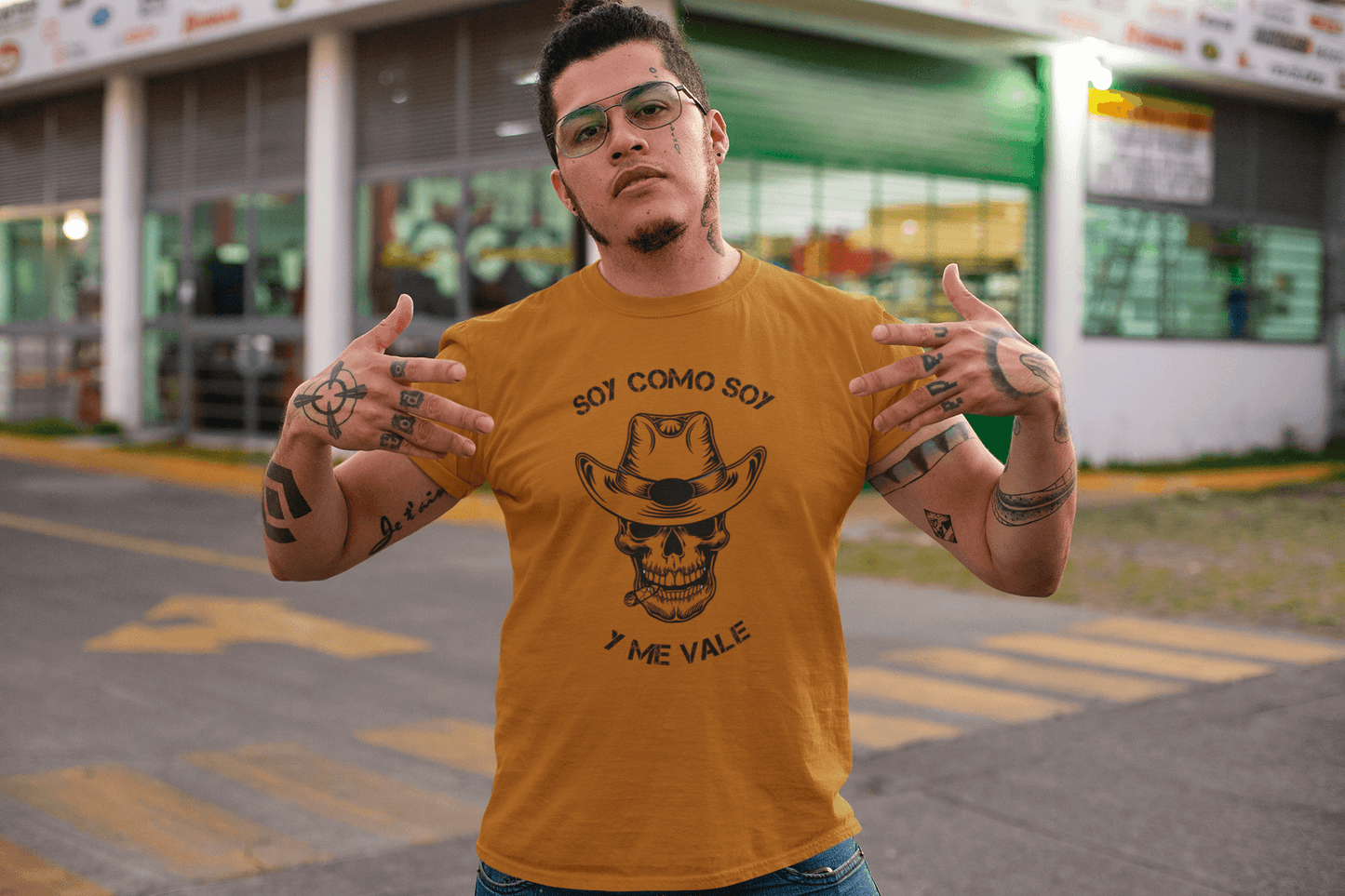 Texas orange t-shirt with black text and design that reads, "Soy Como Soy Y Me Vale" and contains a skull with cowboy hat. It is available in sizes SM-4XL at www.sanchezhere.com